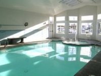 Image: An indoor pool with a bank of windows, and a circular step-in hot tub.